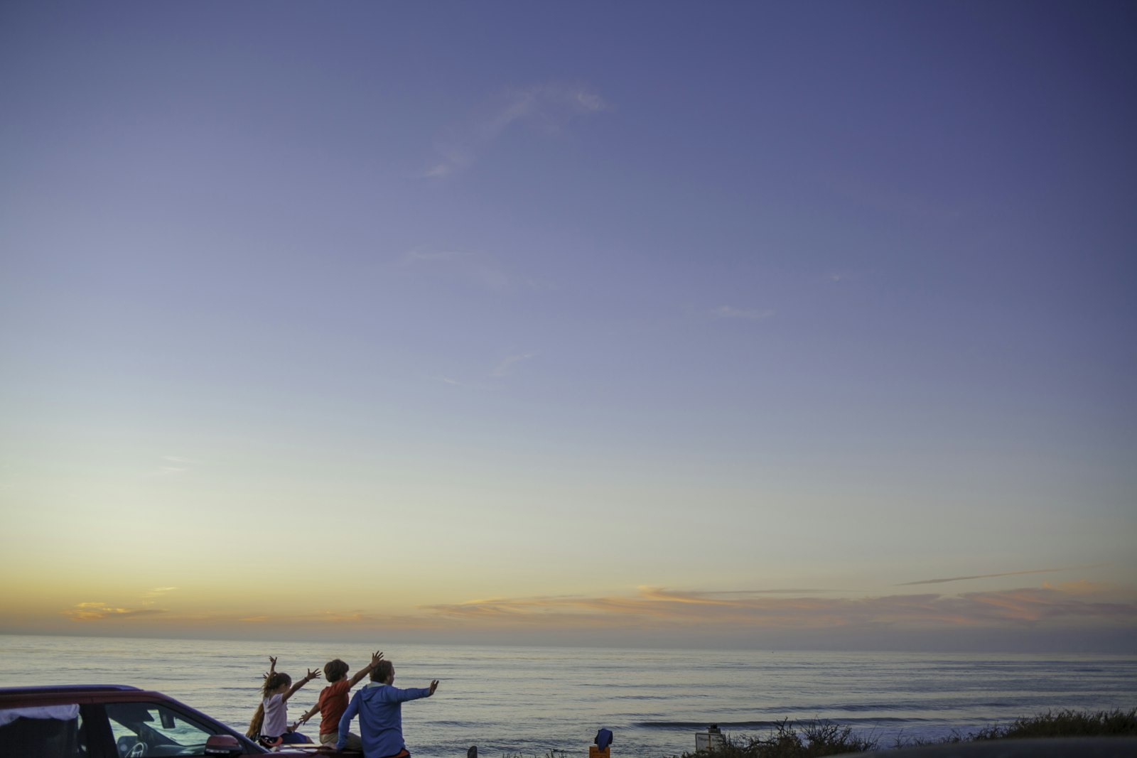 Friend throwing their arms up in celebration on a coastal cliff