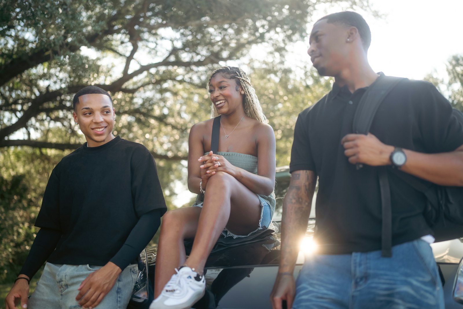 Three friends talking and laughing outdoors on a sunny day