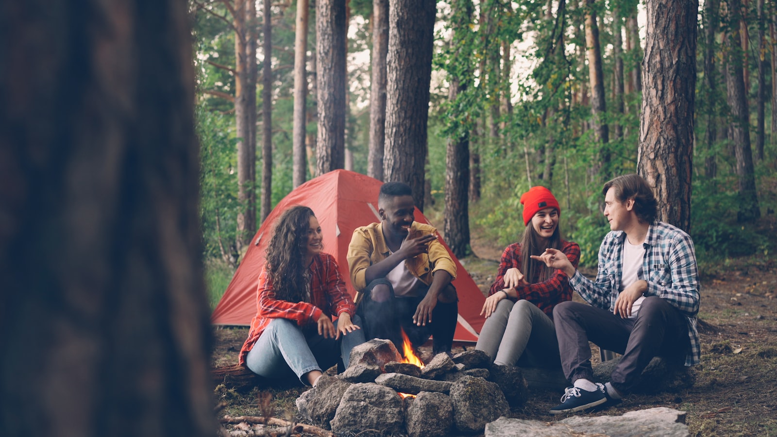 Friends sharing stories and laughing around a campfire at night